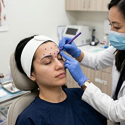 Врач-косметолог выполняет chemical brow lift: введение ботулотоксина под бровь